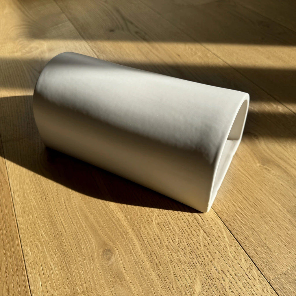 4. Flat lay of off-white ceramic wall sconce by Ora on wooden floor