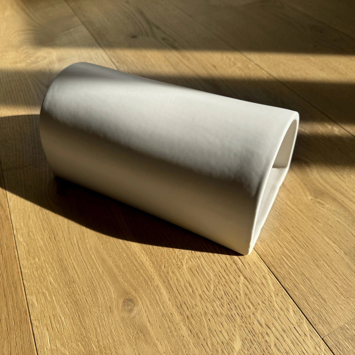 4. Flat lay of off-white ceramic wall sconce by Ora on wooden floor