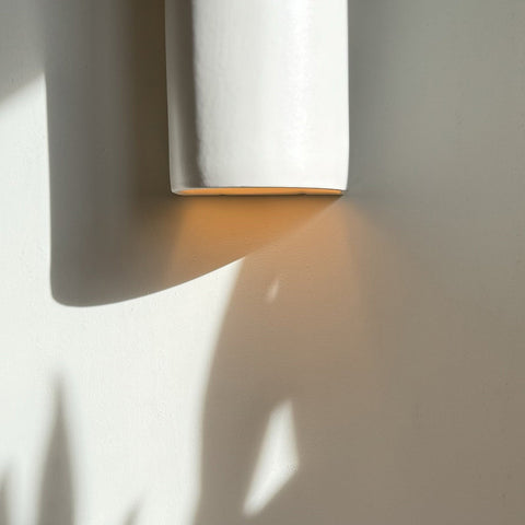 3. Close-up of off-white ceramic wall sconce by Ora casting shadow