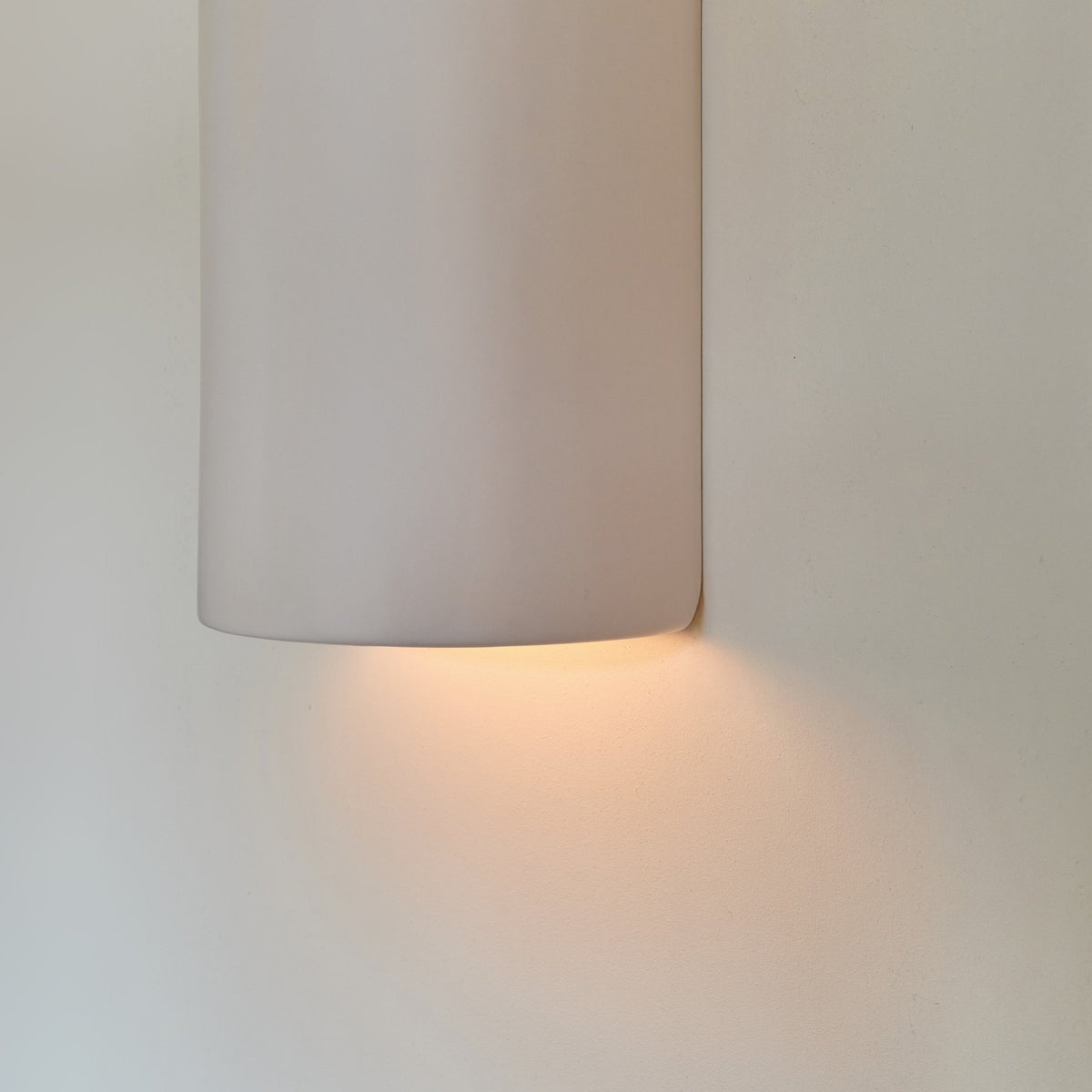 3. Close-up of off-white ceramic wall sconce by Ora with warm light