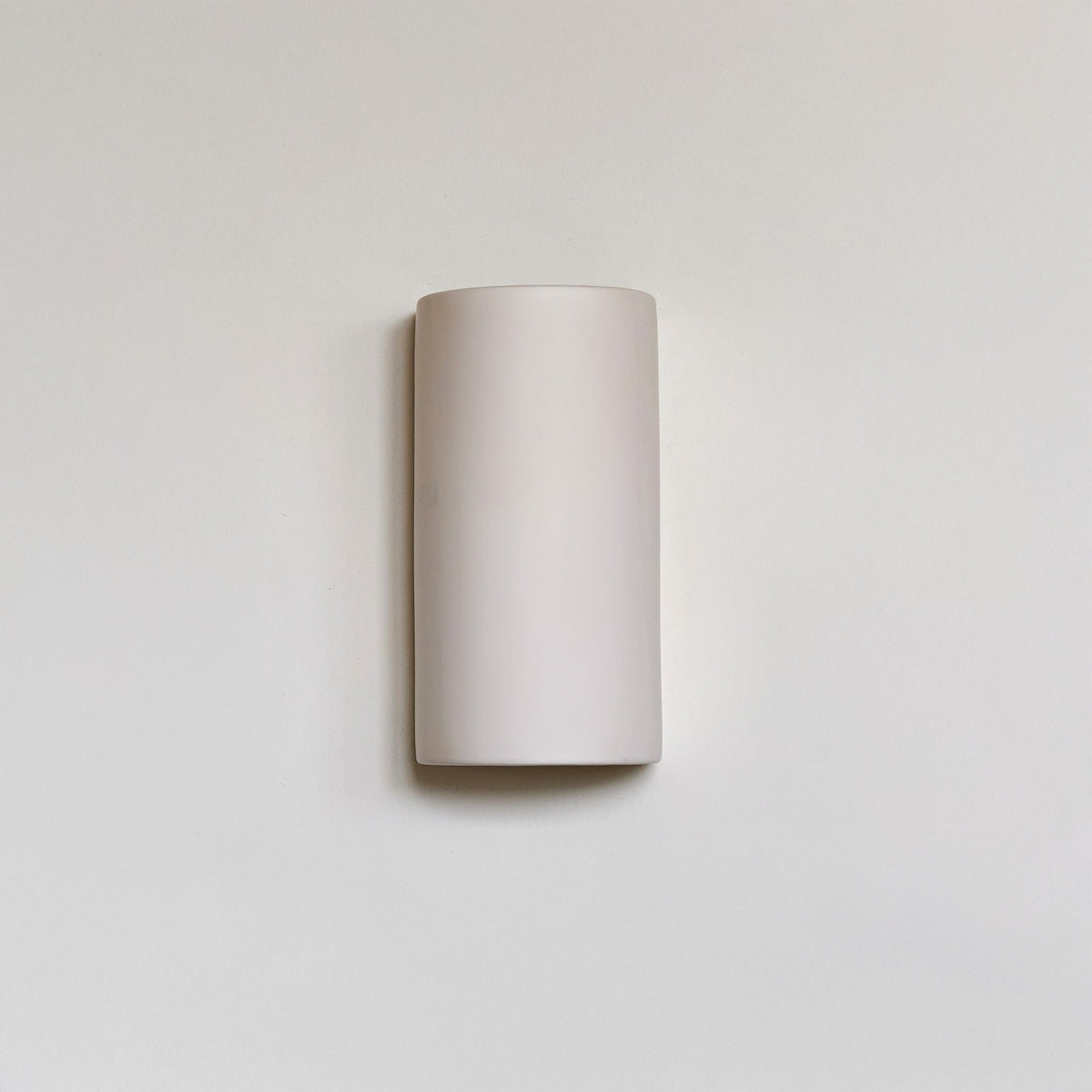 2. Off-white ceramic wall sconce by Ora on a plain background
