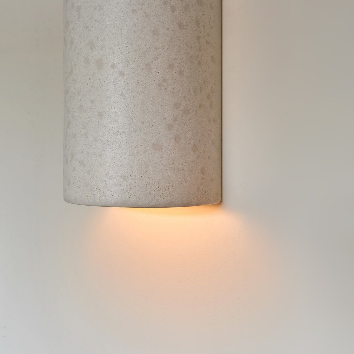 3. Close-up of ceramic wall light in raw white with warm light glow