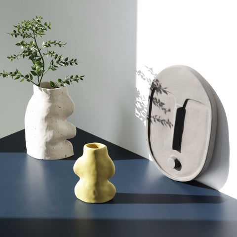 1. Ceramic wall mask in anthracite grey by 5mm Paper, displayed with artistic vases on a modern table
