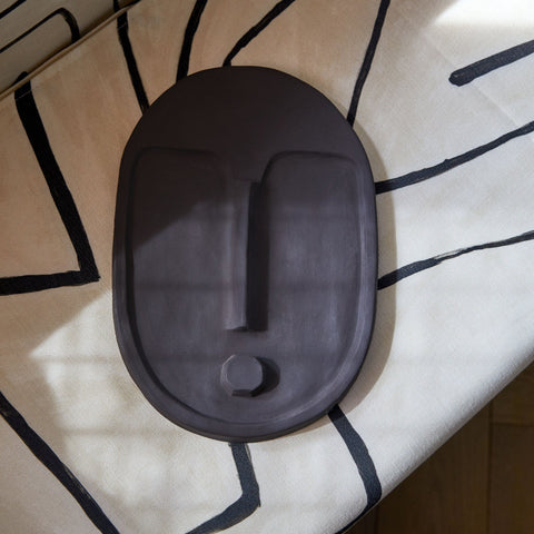 5. Close-up of anthracite grey ceramic wall mask by 5mm Paper, placed on a patterned surface