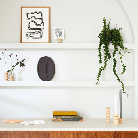 3. Anthracite grey ceramic wall mask by 5mm Paper, styled on a decorative shelf with plants and books