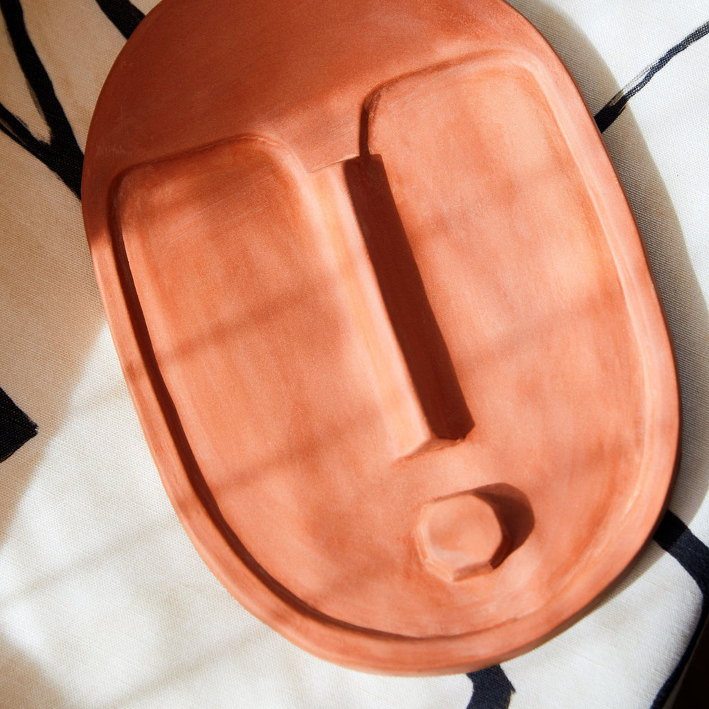 6. Close-up of terracotta orange ceramic wall mask by 5mm Paper on a patterned surface