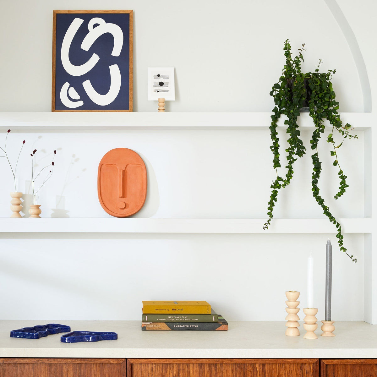 3. 5mm Paper ceramic wall mask in terracotta orange on a shelf with modern decor and plants