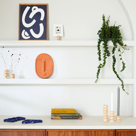 3. 5mm Paper ceramic wall mask in terracotta orange on a shelf with modern decor and plants