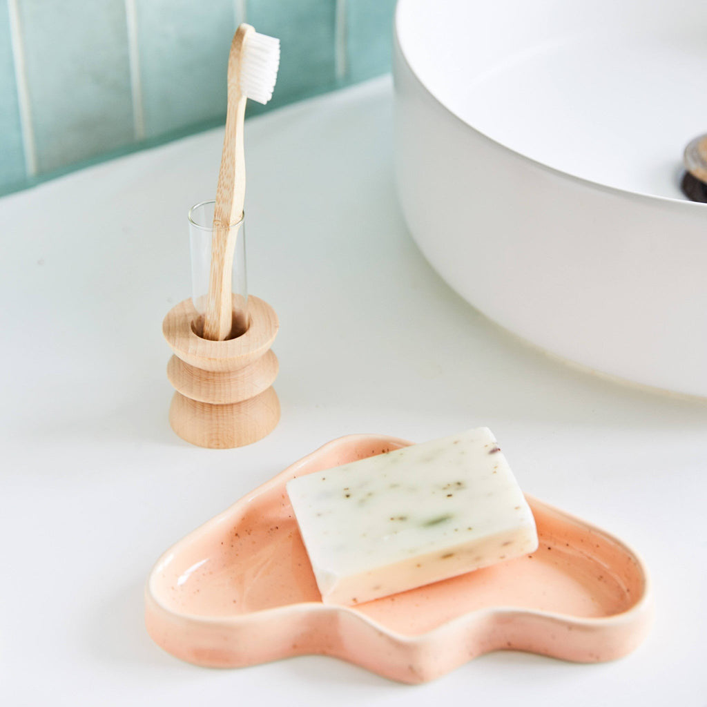 1. Ceramic Wave Tray in peach triangle design on bathroom counter with soap, showcasing speckled finish