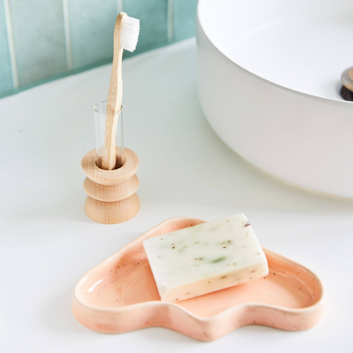 1. Ceramic Wave Tray in peach triangle design on bathroom counter with soap, showcasing speckled finish
