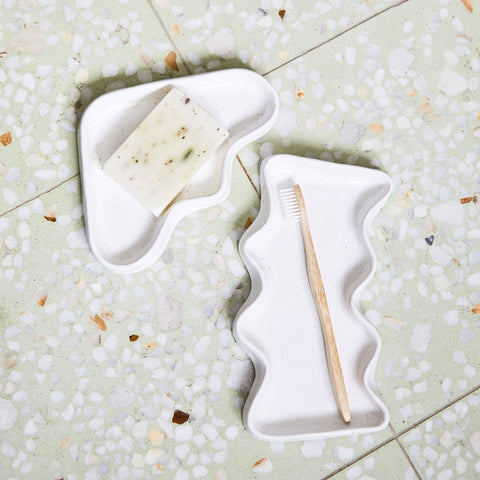 1. Ceramic Wave Tray in speckled white used as a bathroom accessory with soap and toothbrush