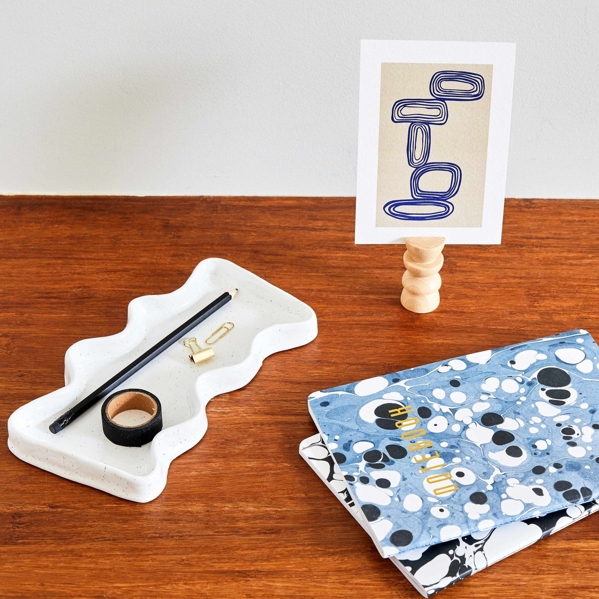 2. Ceramic Wave Tray in speckled white on a desk with stationery and notebooks