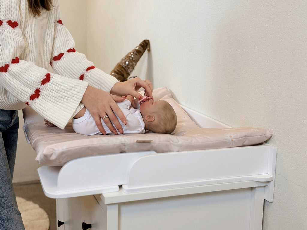 5. Close-up of baby on pink changing table mat with woman adjusting