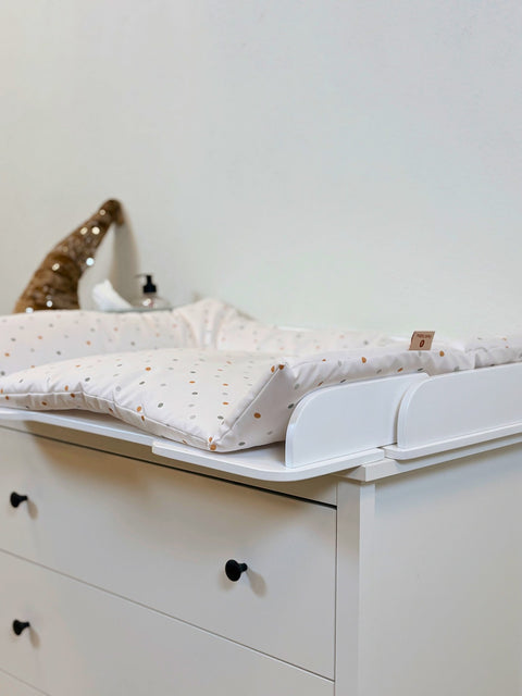 1. White changing table mat with polka dots on a dresser in a nursery setting