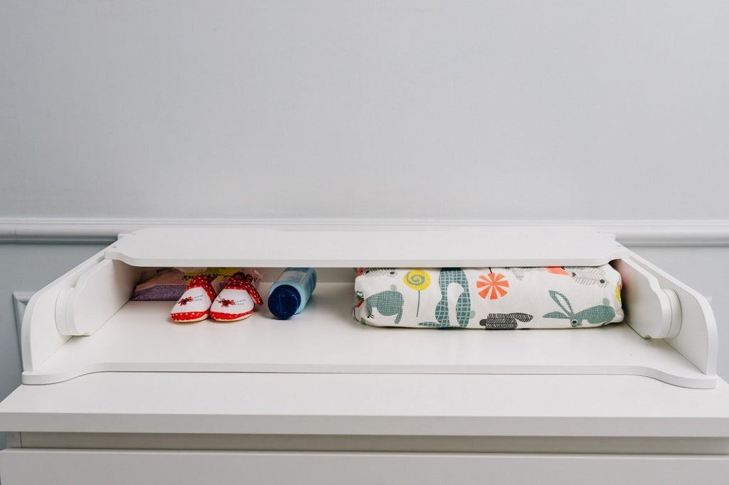 8. White changing table top with baby shoes, bottle, and colorful mat in a nursery
