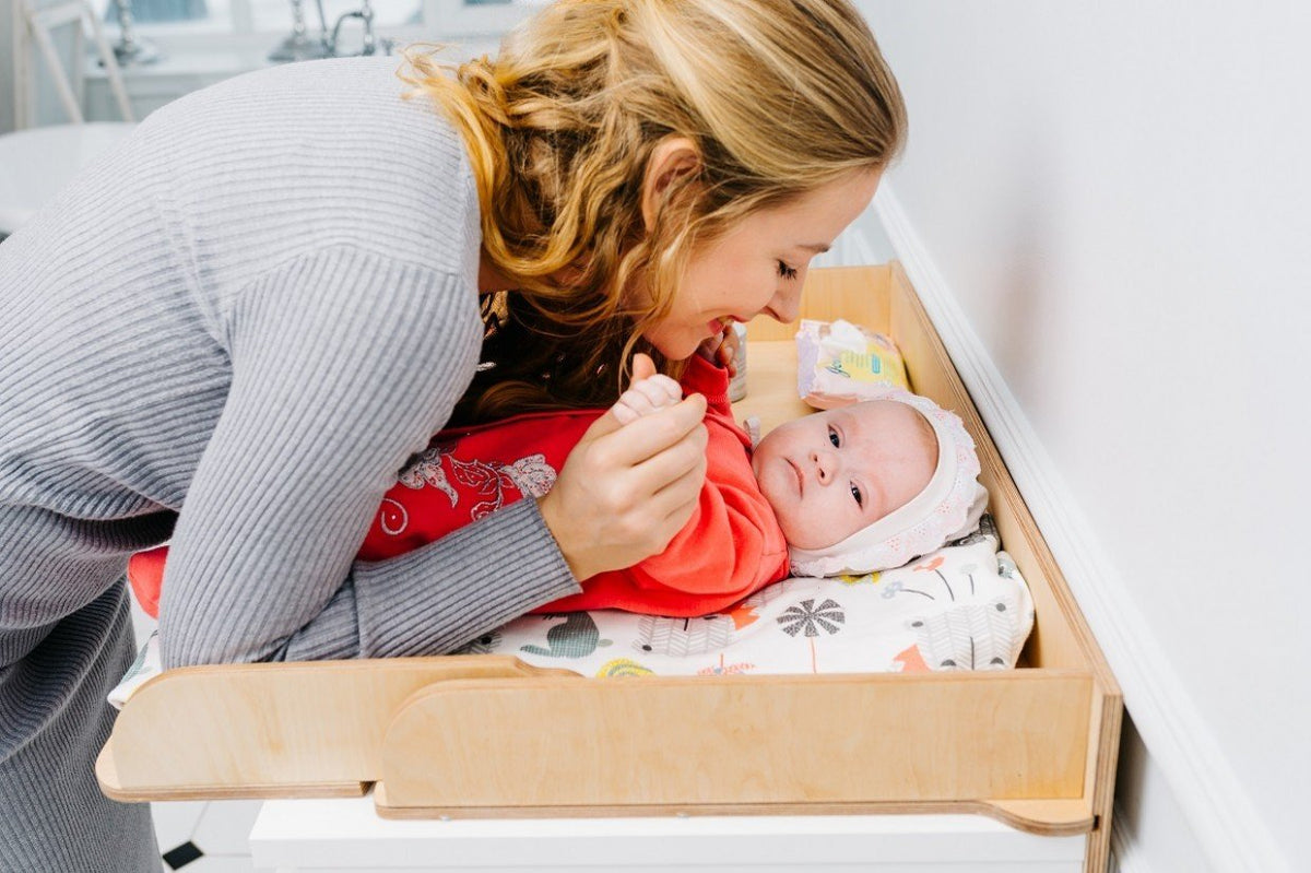 6. Woman interacting with baby on birch plywood changing table top in a nursery
