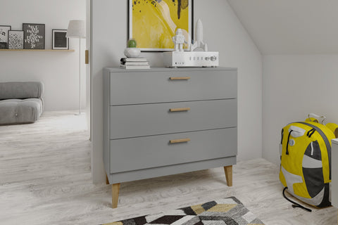 4. Kocot Kids Kubi grey chest of drawers in a modern room setting with decorative items on top