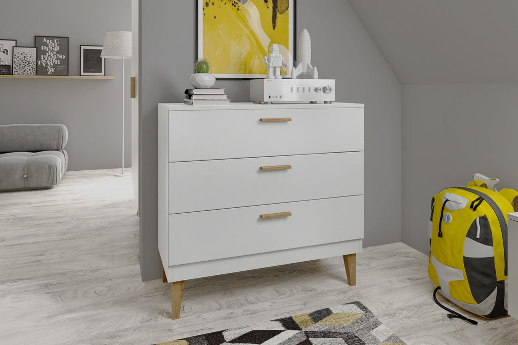 1. White chest of drawers with oak handles in a modern children's room with grey walls and a yellow backpack
