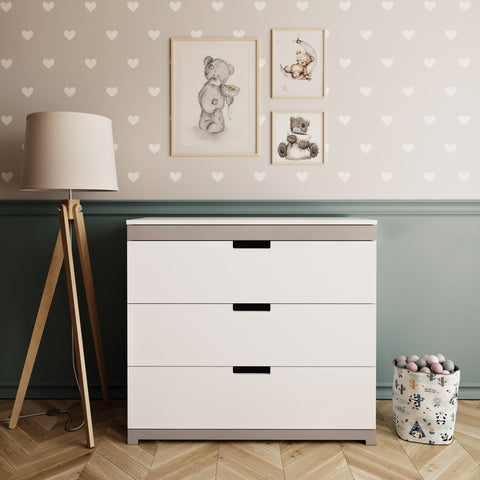 1. White chest of drawers with grey accents in a children's room setting, featuring heart-patterned wallpaper, a floor lamp, and framed teddy bear art