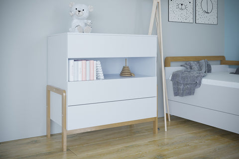 1. White chest of drawers with oak legs in a child's room, featuring books and a teddy bear on top