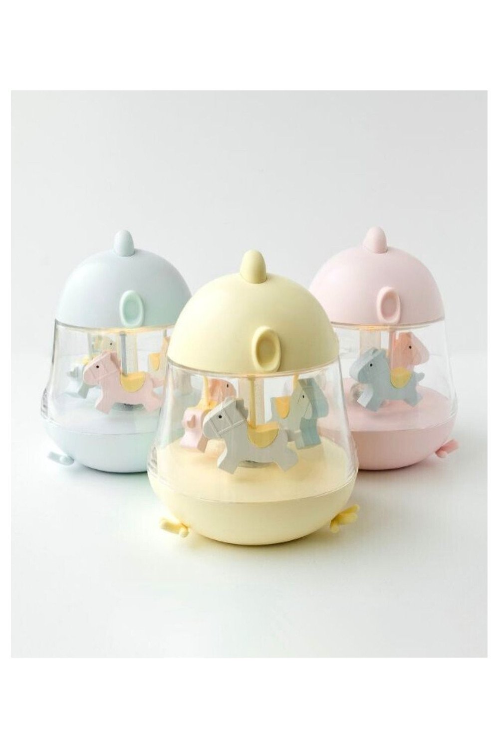 4. Flat lay of three Rabbit & Friends lamps in pastel yellow, pink, and blue with carousel horses