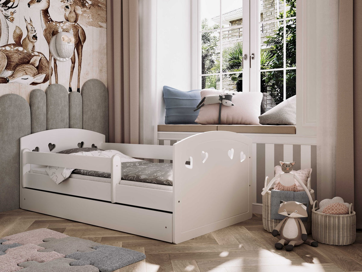 1. White children's bed with heart-shaped cutouts and movable guardrail in a cozy room with plush toys and a window view
