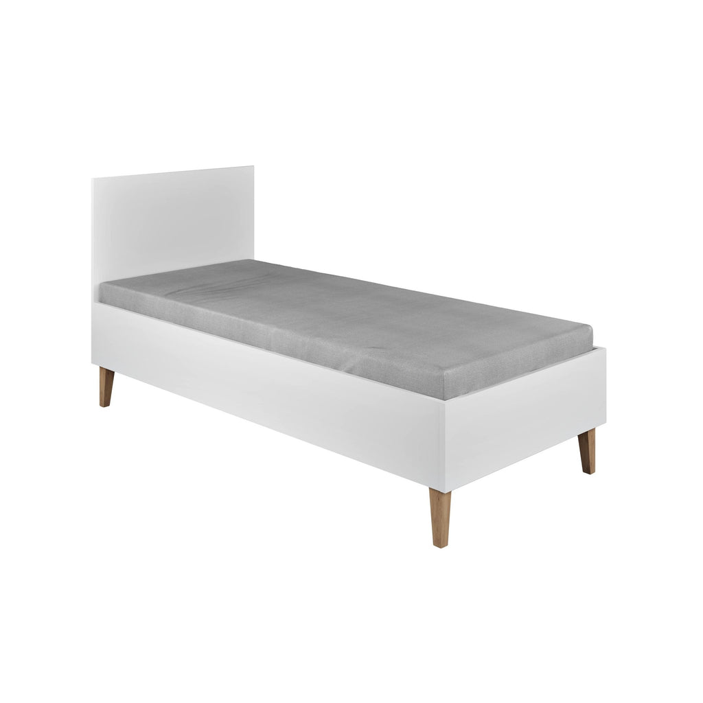 2. White children's bed with solid oak legs and grey mattress in a studio setting
