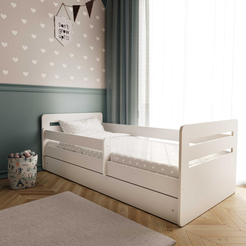 5. White children's bed with patterned bedding in a cozy room with heart wallpaper