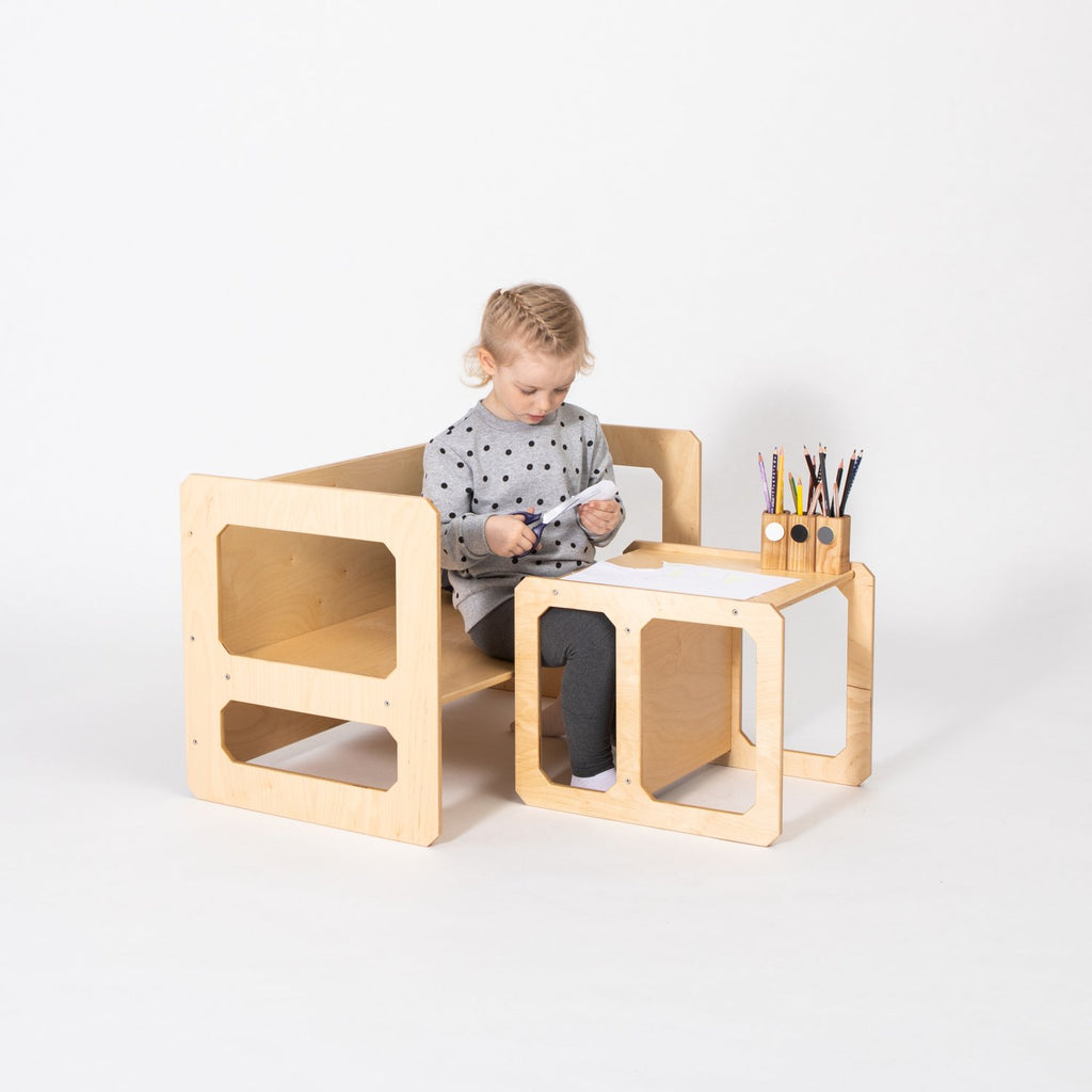 1. Child sitting at a natural wood Montessori weaning table and chair set with art supplies on a white background