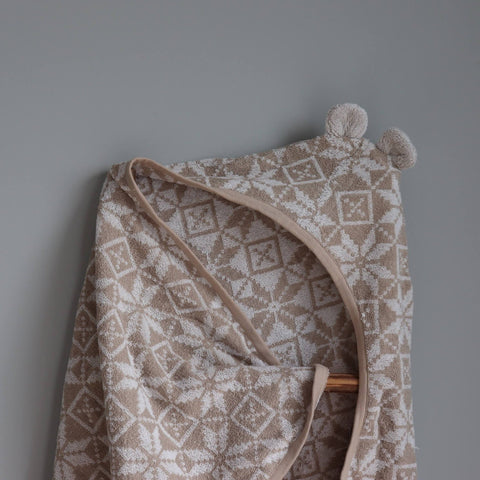 2. Close-up of beige children's hooded towel with teddy bear ears and Hiiumaa mitten pattern on neutral background