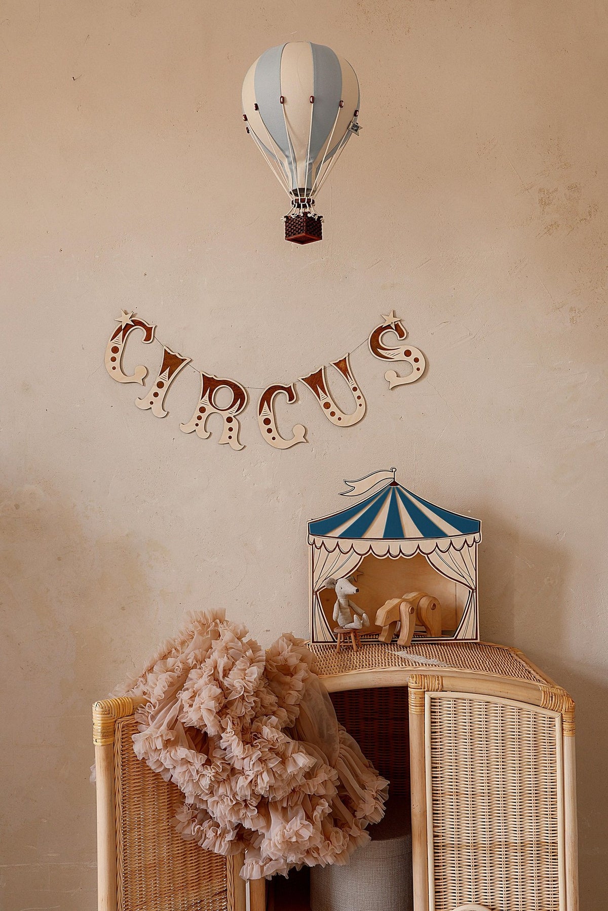 6. Children's room with blue and white circus puppet theater on wicker cabinet, featuring plush toys and hot air balloon decor
