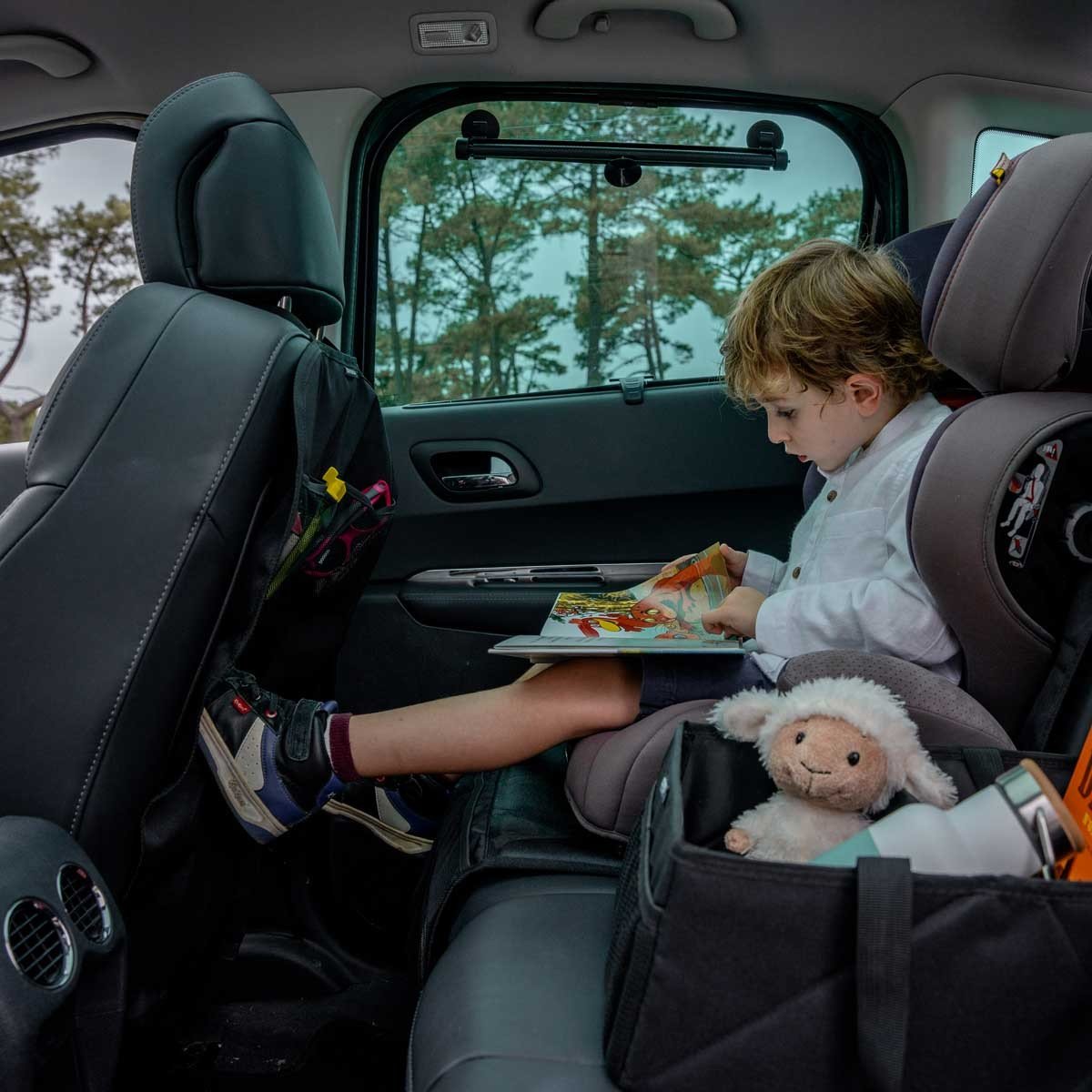 1. Child reading in car with Ezimoov seat organizer storing items in backseat