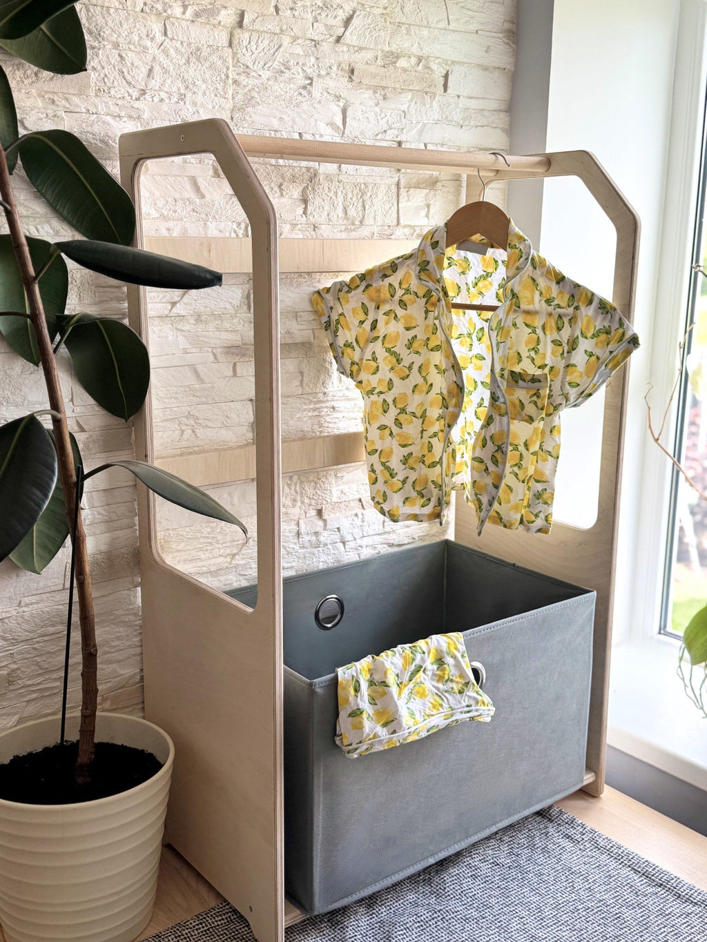 2. Montessori wooden clothes drying rack with yellow patterned shirt and grey fabric basket