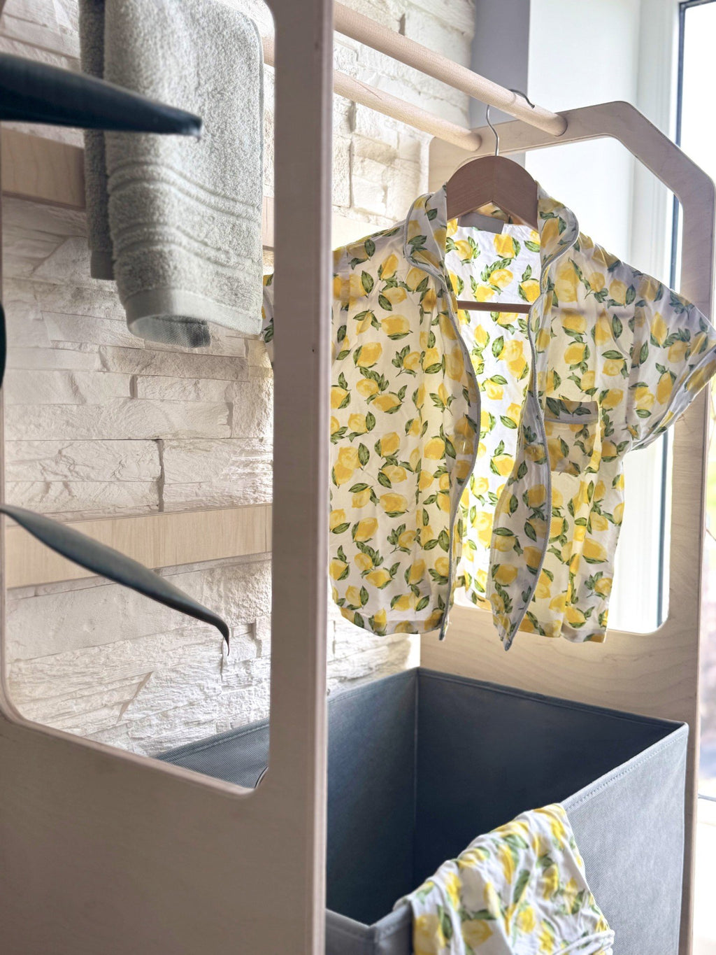 7. Wooden clothes drying rack with lemon print shirt and grey towel in a bright room