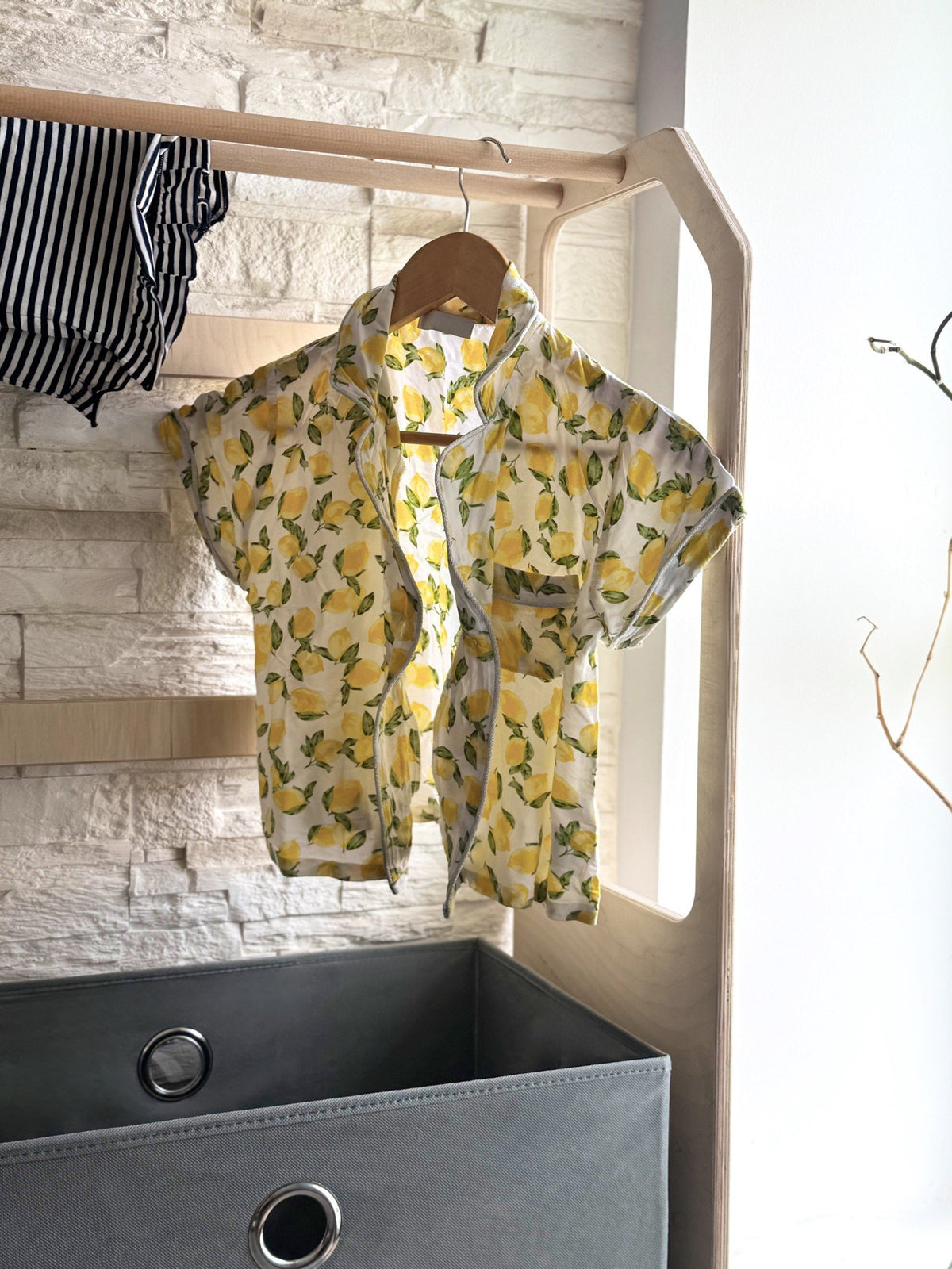 6. Wooden clothes drying rack with yellow lemon print shirt and grey fabric basket