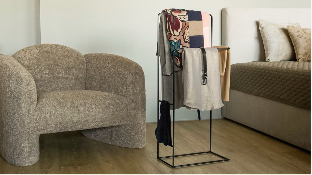 1. Black clothes rack stand holding various garments in a cozy bedroom setting with a chair and bed