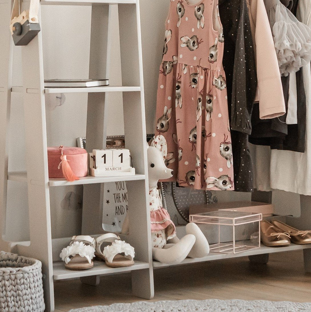 18. Close-up of grey clothing rack with toddler clothes and toys in a nursery