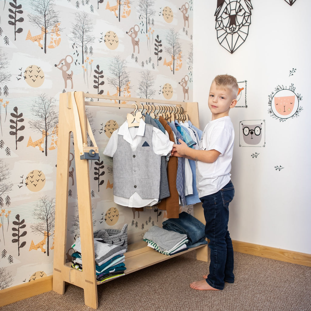 8. Child interacting with a natural wood toddler clothing rack in a playful room setting