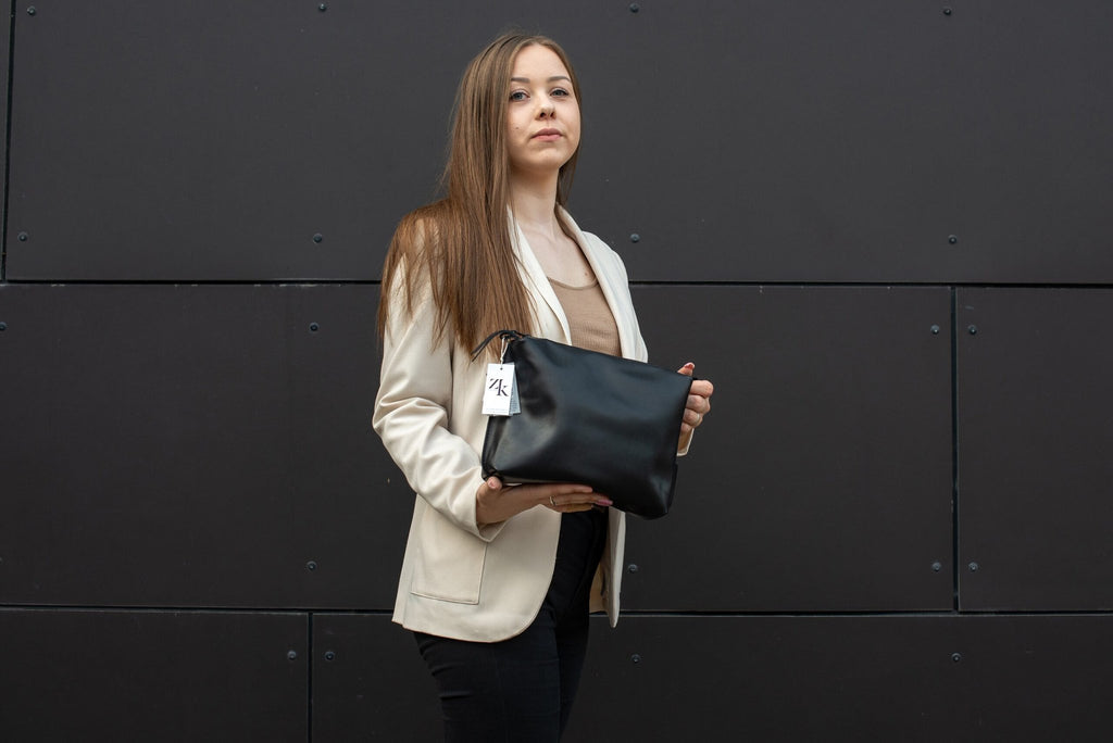 1. Woman holding Zelma Kraft large black leather cosmetic bag, showcasing elegant design and size