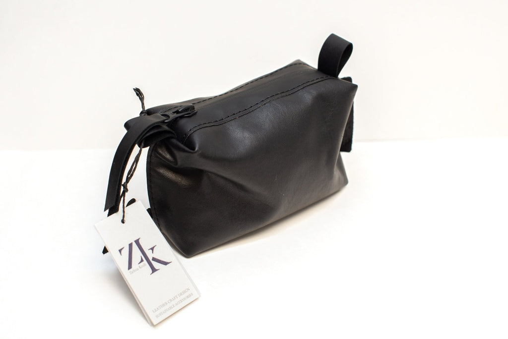 4. Studio shot of Zelma Kraft black leather cosmetic bag with tag, featuring zipper closure and durable design