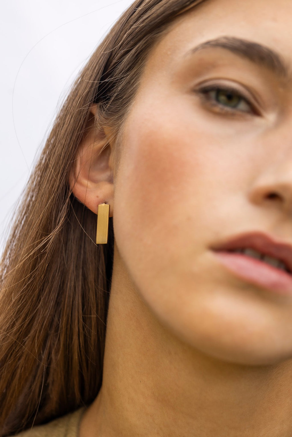 3. Close-up of Lentsius Sunlit earring with golden PVD TiCN coating on woman's ear