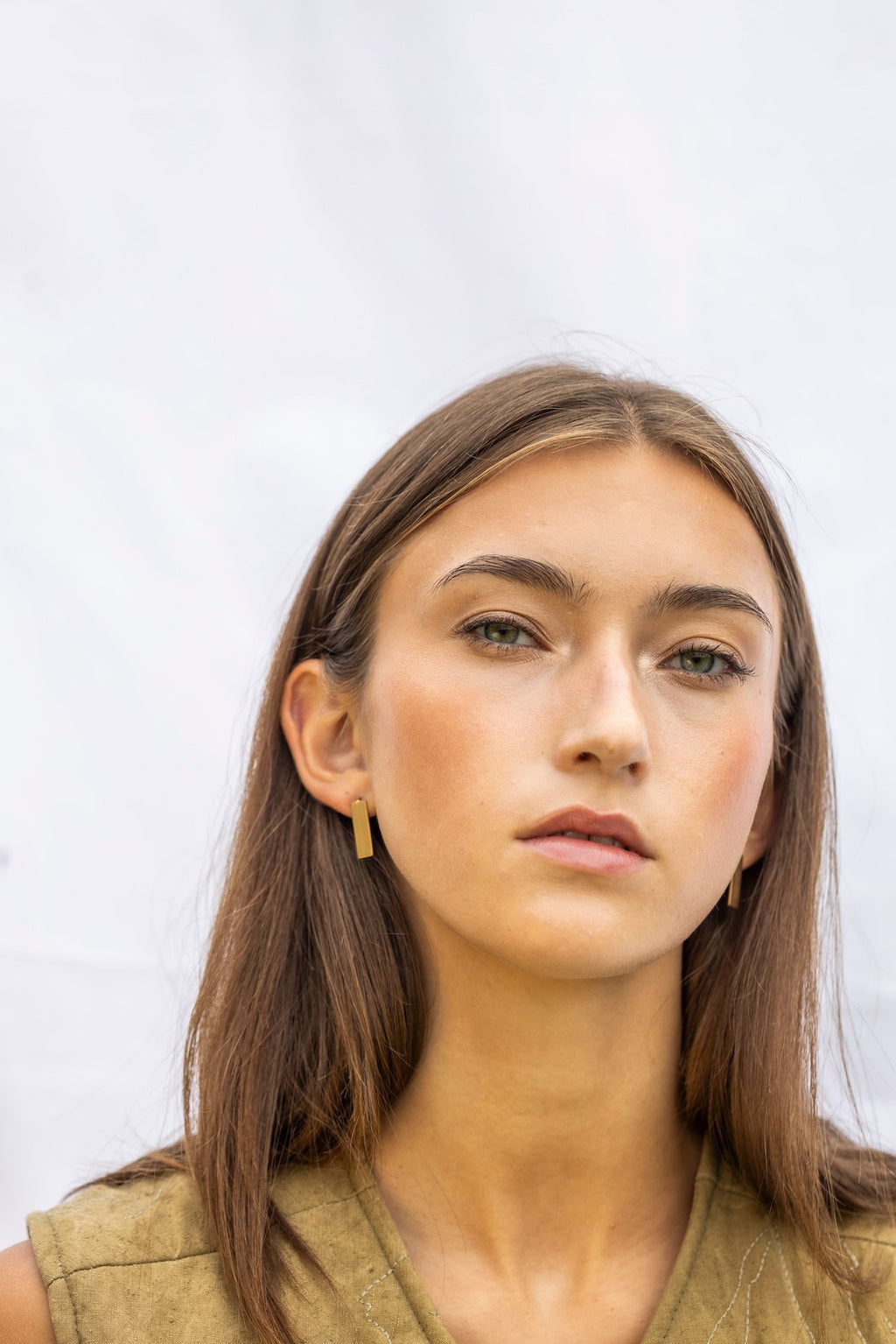1. Woman wearing Lentsius Sunlit earrings, looking forward against a light background