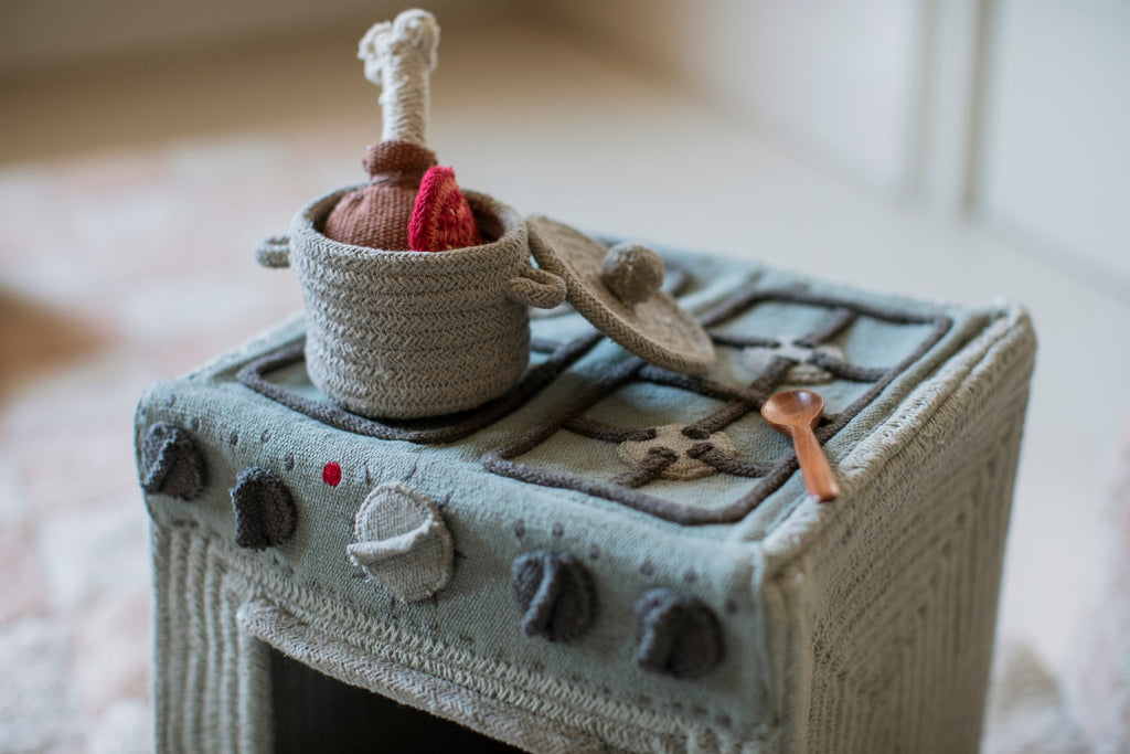 3. Close-up of Lorena Canals blue sage textile toy stove with pot and spoon on cooktop