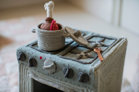 3. Close-up of Lorena Canals blue sage textile toy stove with pot and spoon on cooktop