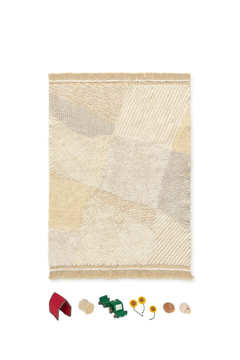 2. Studio shot of Lorena Canals cotton play rug in natural colors with farm-themed cotton toys including a mini stable, tractor, sunflowers, hen, and haystack