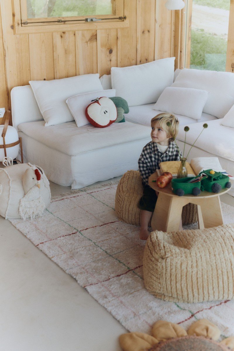 1. Child sitting on natural cotton rug with multicolor stripes in a playroom setting