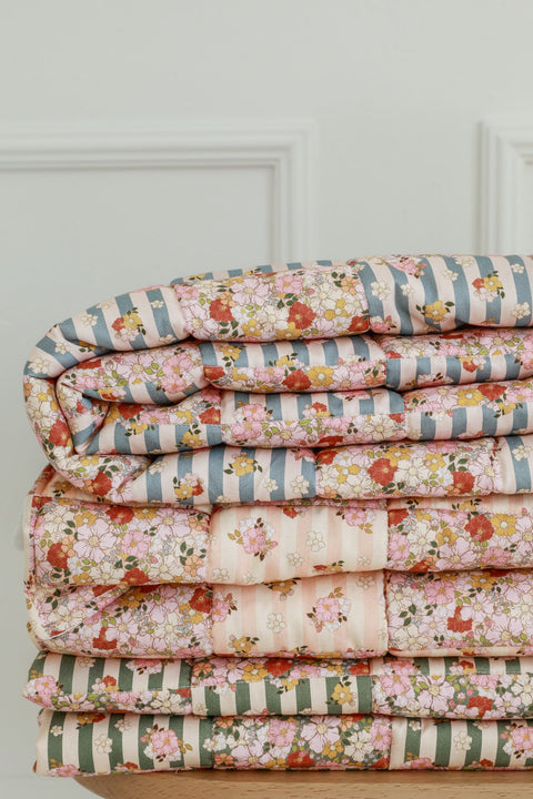 4. Stack of folded Moi Mili cotton quilted patchwork blankets in various floral patterns