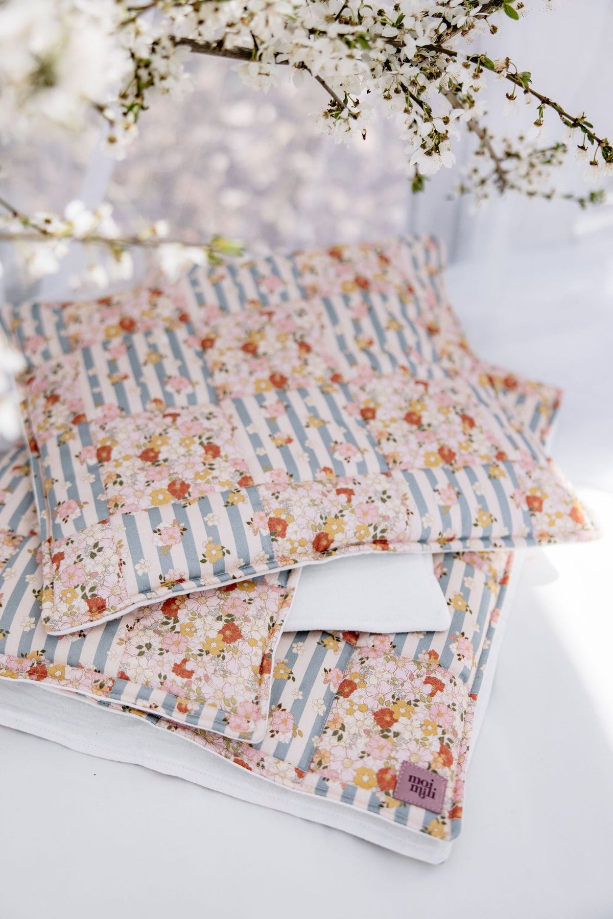 6. Moi Mili cotton quilted patchwork blanket and pillow set outdoors with floral and striped pattern