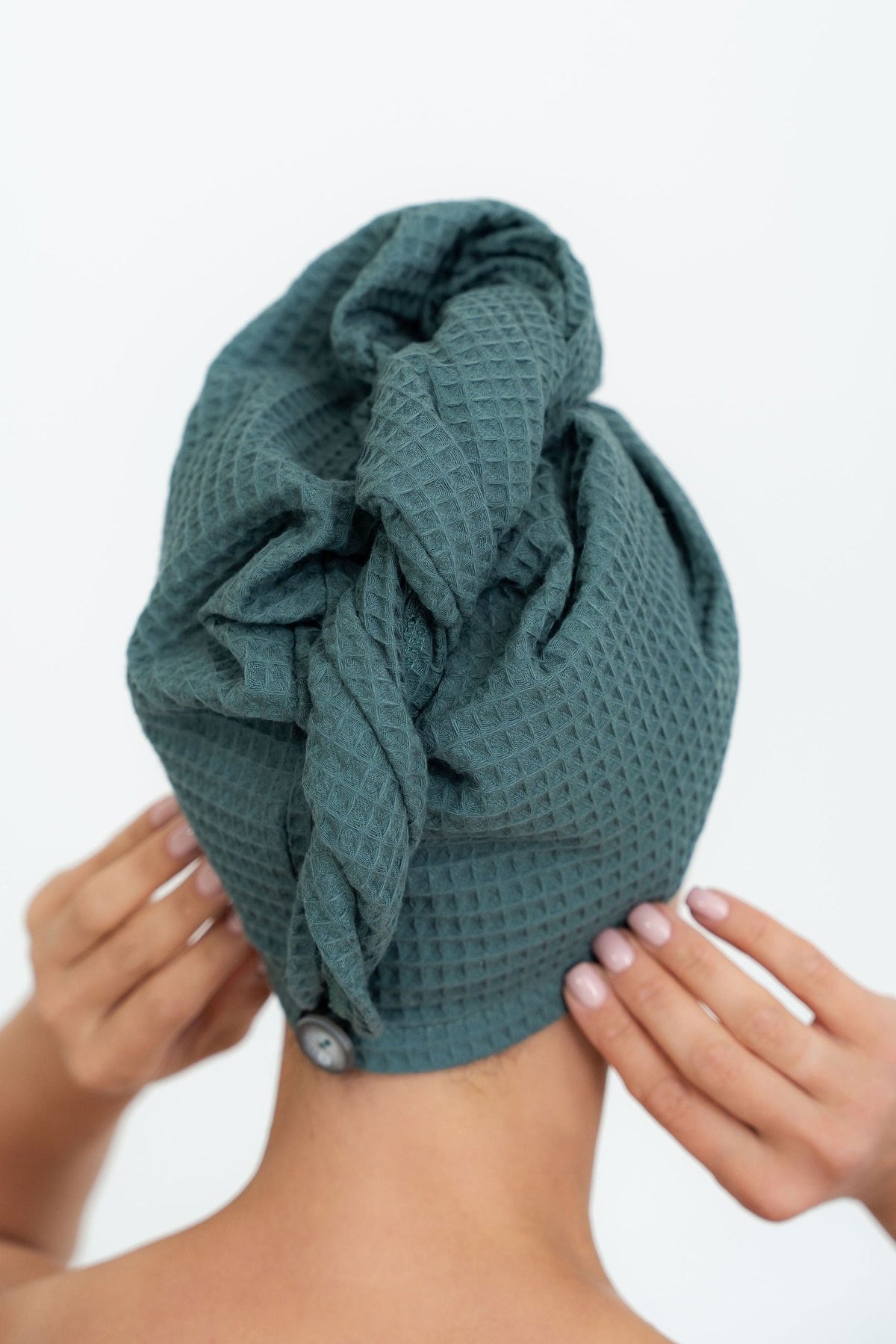 6. Woman adjusting green cotton waffle hair towel turban from back view
