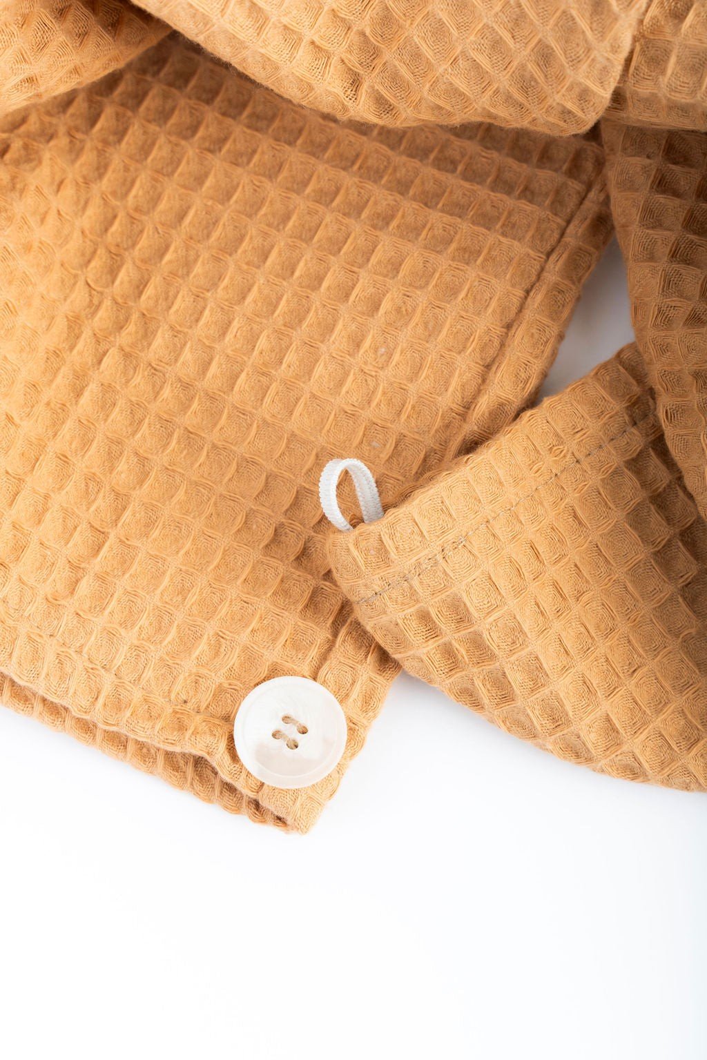 12. Close-up of button and elastic detail on orange cotton waffle hair towel turban